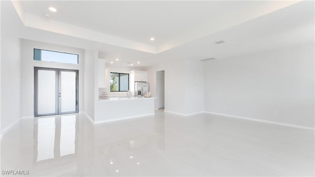 empty room with french doors and a raised ceiling