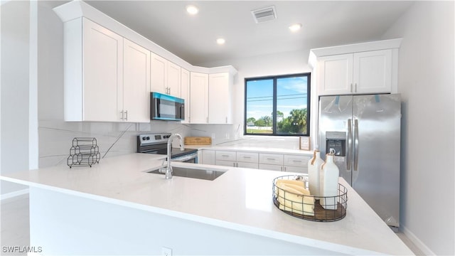 kitchen with sink, stainless steel appliances, white cabinetry, and kitchen peninsula