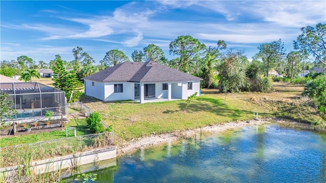 back of property with a lanai, a yard, and a water view