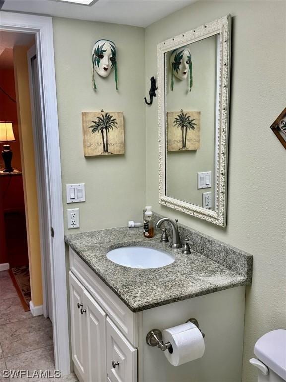 bathroom with tile patterned flooring, vanity, and toilet