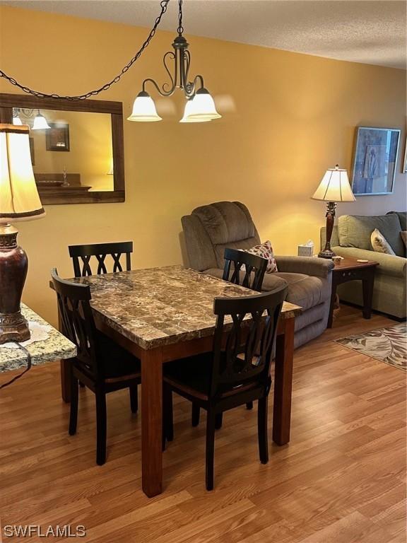 dining space featuring a textured ceiling, hardwood / wood-style flooring, and an inviting chandelier