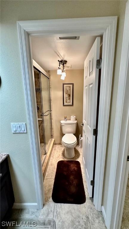 bathroom featuring a shower with door, vanity, and toilet