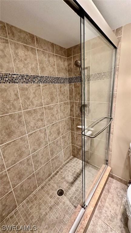 bathroom featuring toilet and a shower with shower door