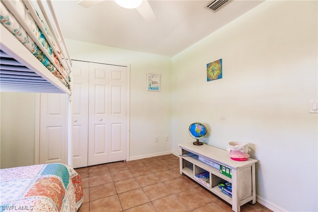 tiled bedroom featuring ceiling fan and a closet