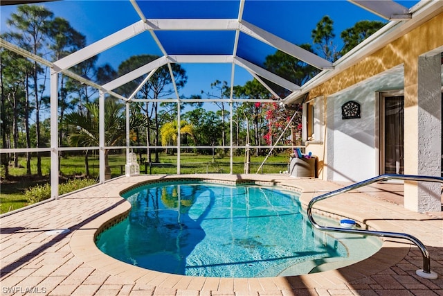 view of swimming pool featuring a lawn, glass enclosure, and a patio area