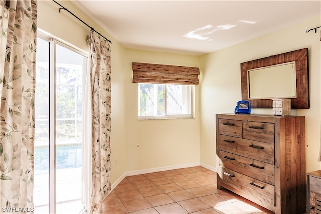 bedroom with multiple windows, access to outside, and light tile patterned floors