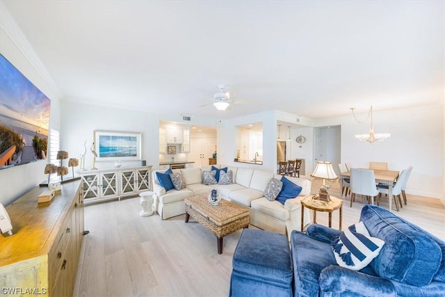 living room featuring ornamental molding, ceiling fan with notable chandelier, and light wood-type flooring