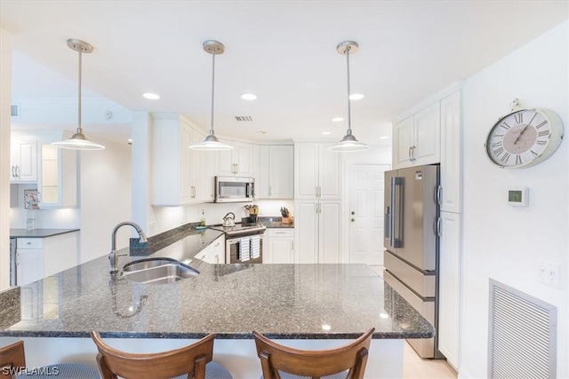 kitchen featuring appliances with stainless steel finishes, sink, white cabinets, a kitchen breakfast bar, and kitchen peninsula