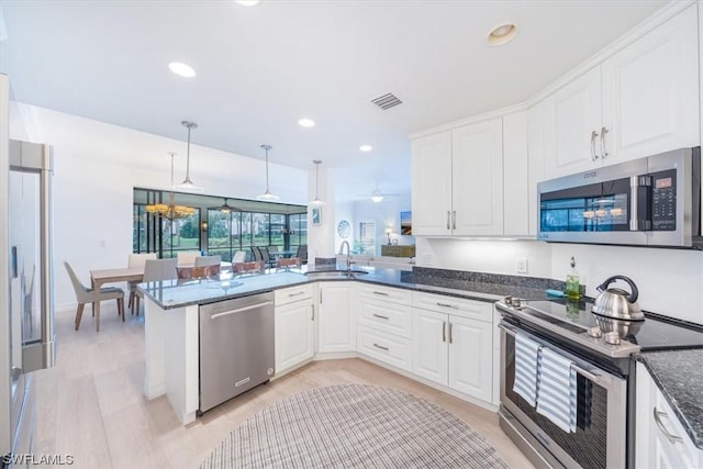 kitchen with sink, appliances with stainless steel finishes, white cabinetry, decorative light fixtures, and kitchen peninsula