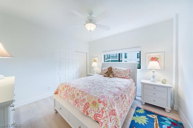 bedroom with light wood-type flooring, ceiling fan, and a closet