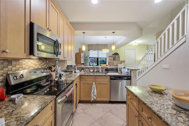 kitchen featuring kitchen peninsula, sink, dark stone counters, stainless steel appliances, and tasteful backsplash