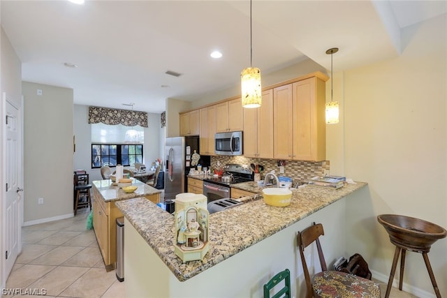 kitchen with light brown cabinetry, a breakfast bar, stainless steel appliances, light stone countertops, and tasteful backsplash