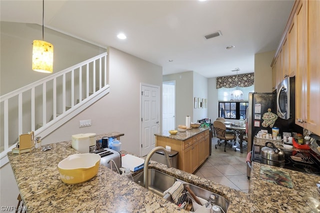 kitchen with light stone countertops, stove, decorative light fixtures, and sink