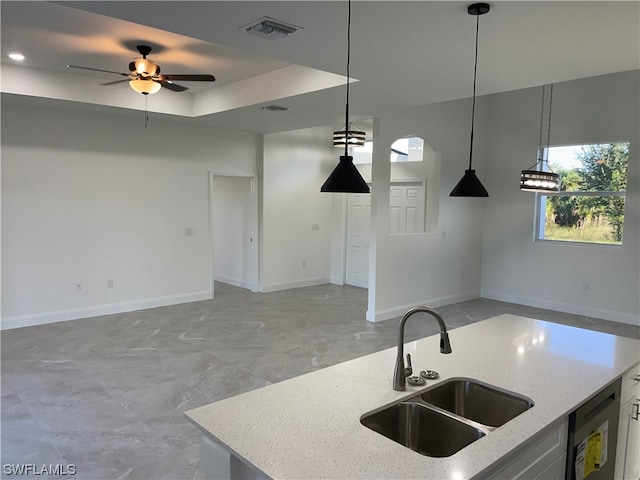 kitchen with a tray ceiling, pendant lighting, light stone countertops, and ceiling fan