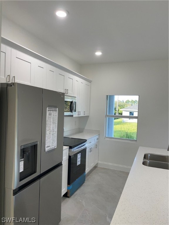 kitchen with white cabinets, stainless steel appliances, light tile floors, and sink