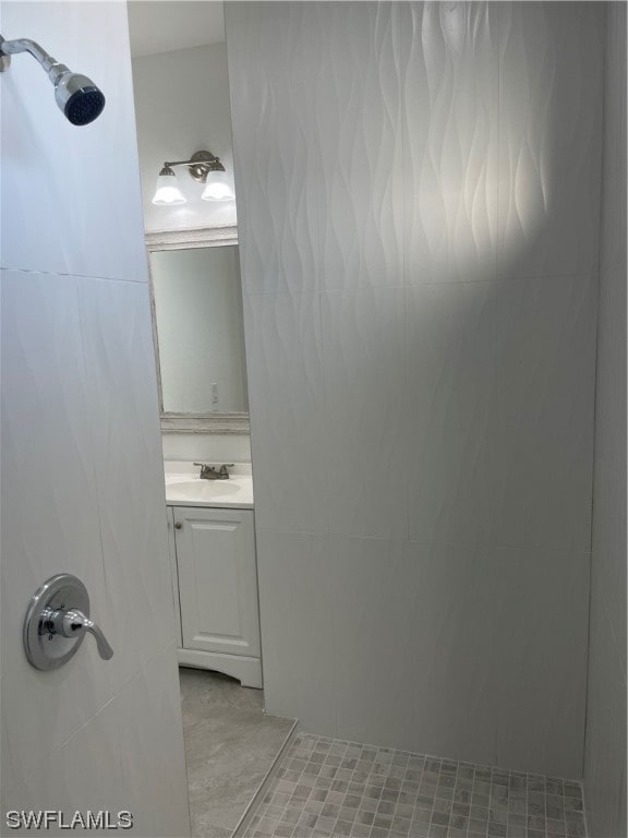 bathroom with vanity with extensive cabinet space, tile flooring, and tiled shower