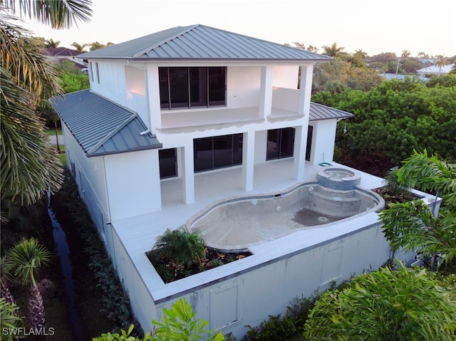 back house at dusk featuring a patio