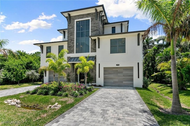 375 Periwinkle Ct, Marco Island, FL 34145 - modern home featuring an attached garage, stone siding, stucco siding, decorative driveway, and a standing seam roof