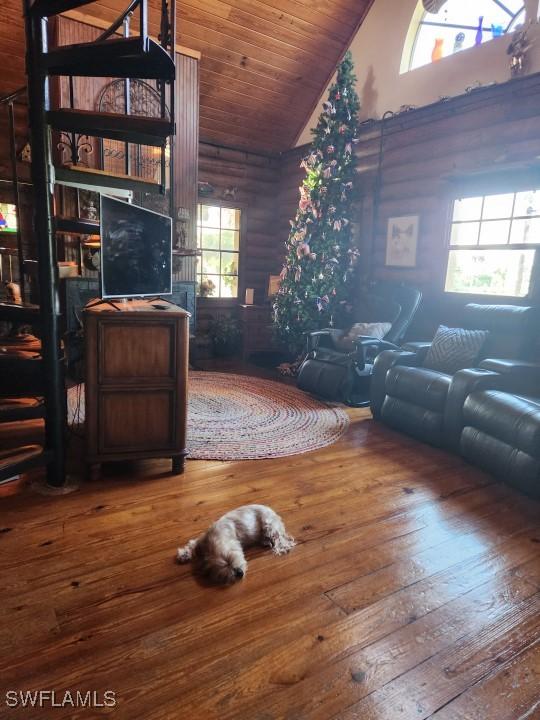 living room featuring hardwood / wood-style floors, log walls, wooden ceiling, and high vaulted ceiling