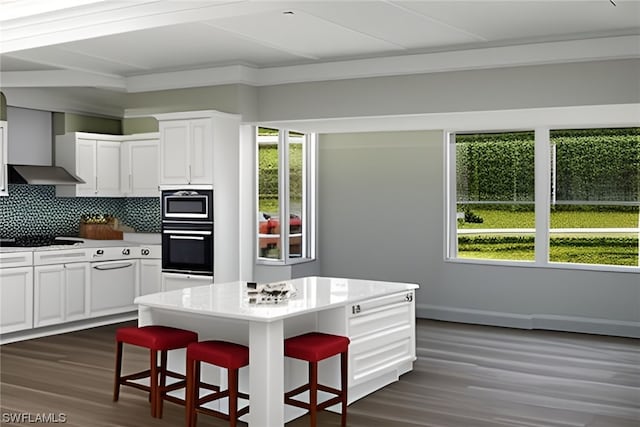 kitchen featuring plenty of natural light, wall chimney exhaust hood, a breakfast bar, and tasteful backsplash