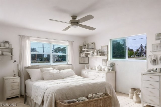 bedroom featuring ceiling fan, light hardwood / wood-style flooring, and multiple windows