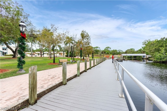 view of dock with a water view and a lawn