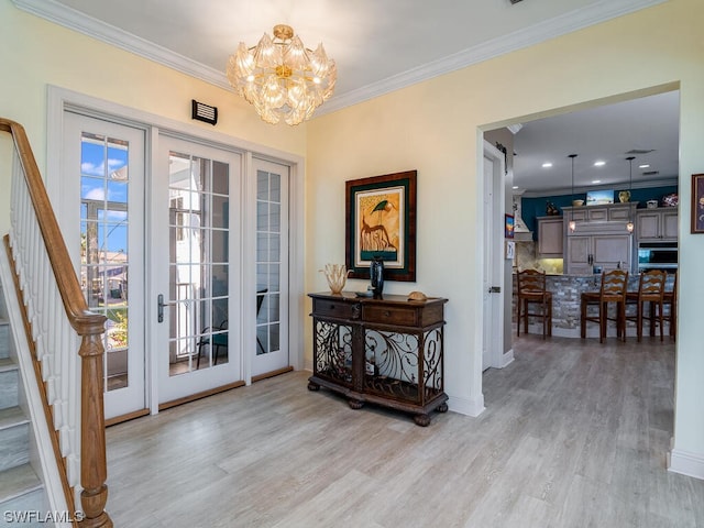 foyer featuring wood-type flooring, ornamental molding, and an inviting chandelier