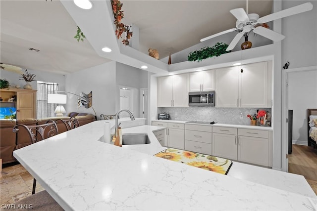 kitchen featuring a kitchen breakfast bar, light stone countertops, sink, and tasteful backsplash