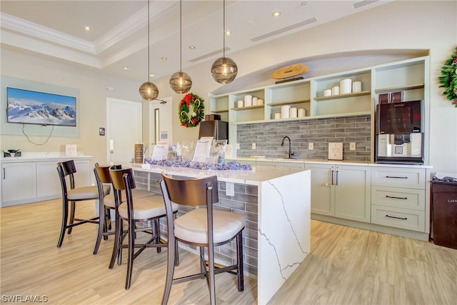 kitchen featuring a kitchen breakfast bar, tasteful backsplash, a kitchen island, and light wood-type flooring