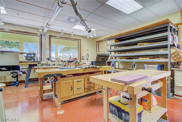 kitchen with a paneled ceiling, light brown cabinets, and concrete floors