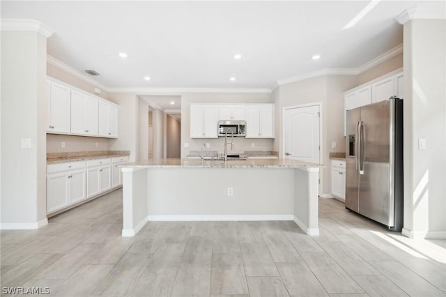 kitchen with light stone countertops, white cabinetry, a center island with sink, and stainless steel appliances