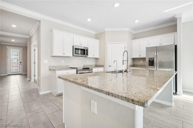 kitchen with stainless steel appliances, a kitchen island with sink, crown molding, sink, and white cabinets