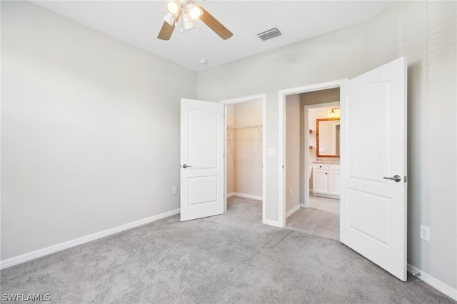 unfurnished bedroom featuring a walk in closet, ceiling fan, a closet, and light carpet