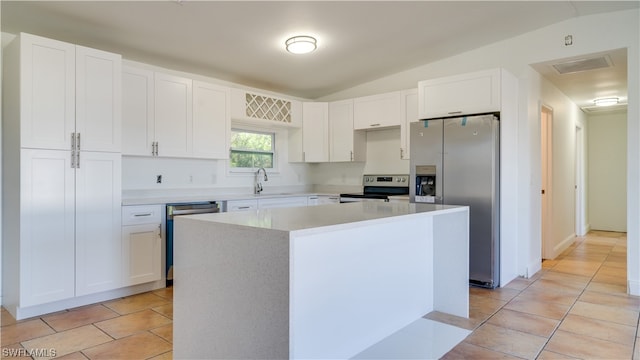 kitchen with a center island, lofted ceiling, appliances with stainless steel finishes, and light tile patterned floors