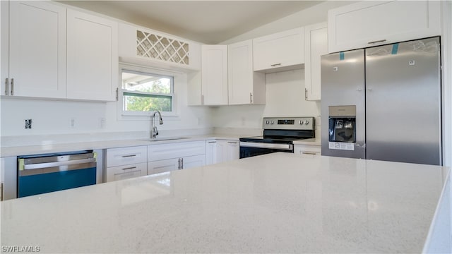 kitchen with sink, light stone counters, stainless steel appliances, and white cabinetry