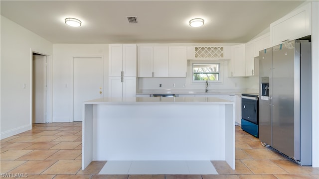 kitchen with white cabinets, appliances with stainless steel finishes, and light tile patterned floors