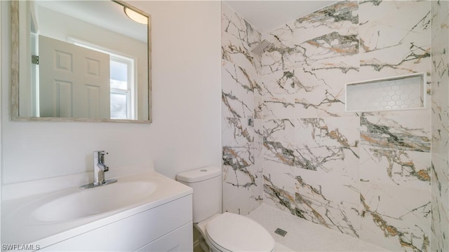 bathroom featuring toilet, vanity, and a tile shower