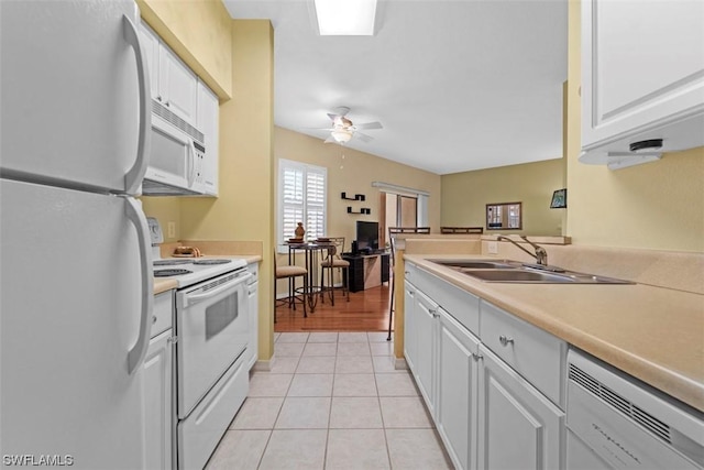 kitchen featuring sink, white appliances, light tile patterned floors, ceiling fan, and white cabinets