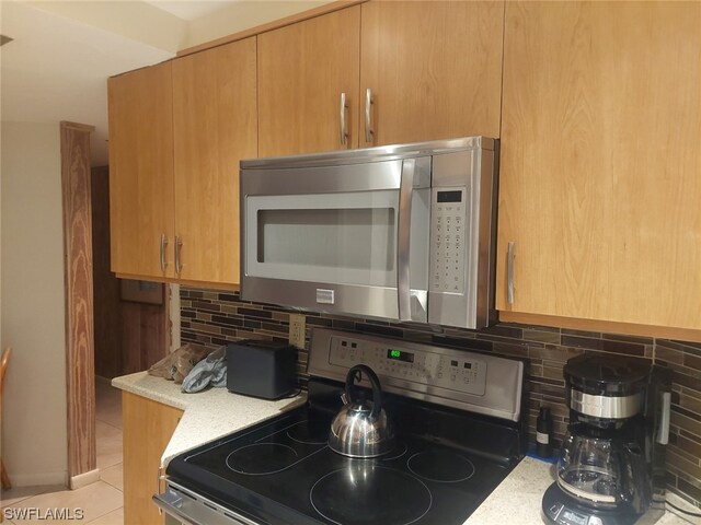 kitchen with electric stove, light stone counters, decorative backsplash, and light tile patterned floors