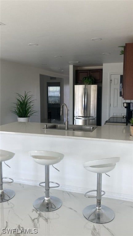 kitchen with stainless steel fridge, a kitchen bar, stove, and sink