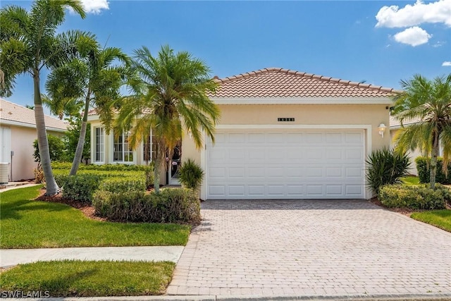 mediterranean / spanish home with a garage and a front lawn