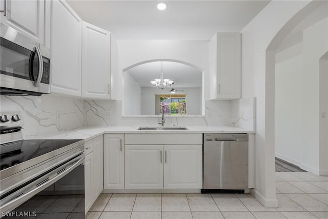 kitchen with light stone countertops, appliances with stainless steel finishes, sink, and white cabinets