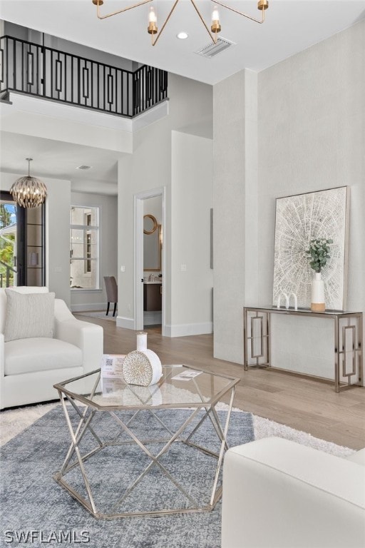 living room featuring a high ceiling, an inviting chandelier, and wood-type flooring