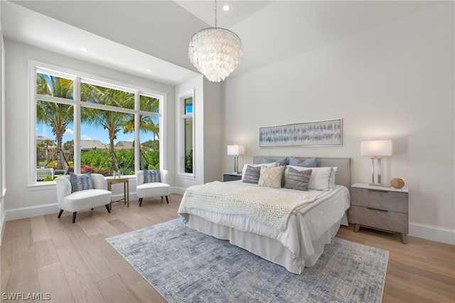 bedroom featuring a high ceiling, a chandelier, and light hardwood / wood-style flooring