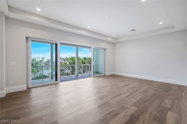 spare room featuring a tray ceiling and hardwood / wood-style floors