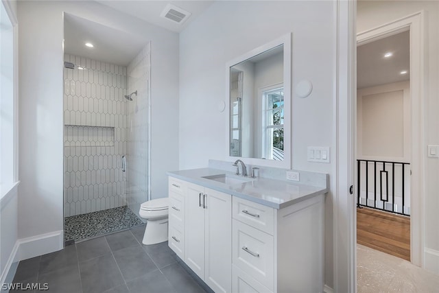 bathroom featuring a tile shower, tile flooring, vanity, and toilet