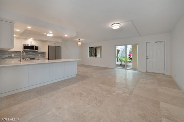 kitchen featuring sink, light tile floors, appliances with stainless steel finishes, tasteful backsplash, and white cabinetry