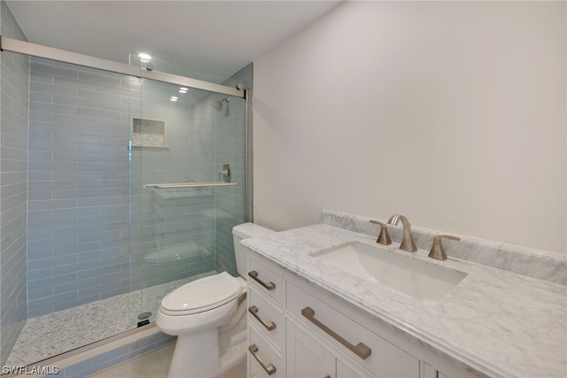 bathroom featuring toilet, vanity, a shower with shower door, and tile flooring