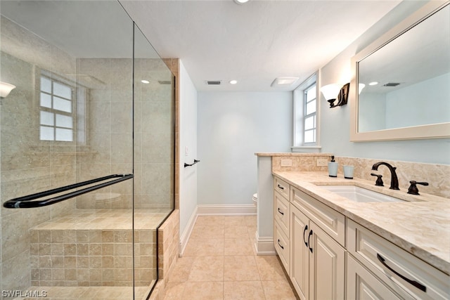 bathroom with a shower with door, vanity, tile patterned flooring, and toilet