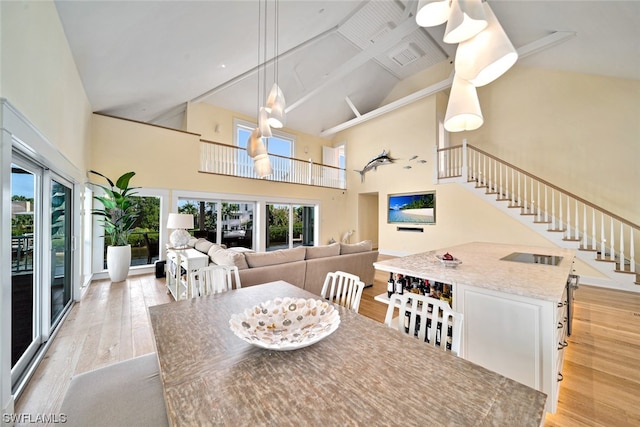 dining space with high vaulted ceiling and light wood-type flooring